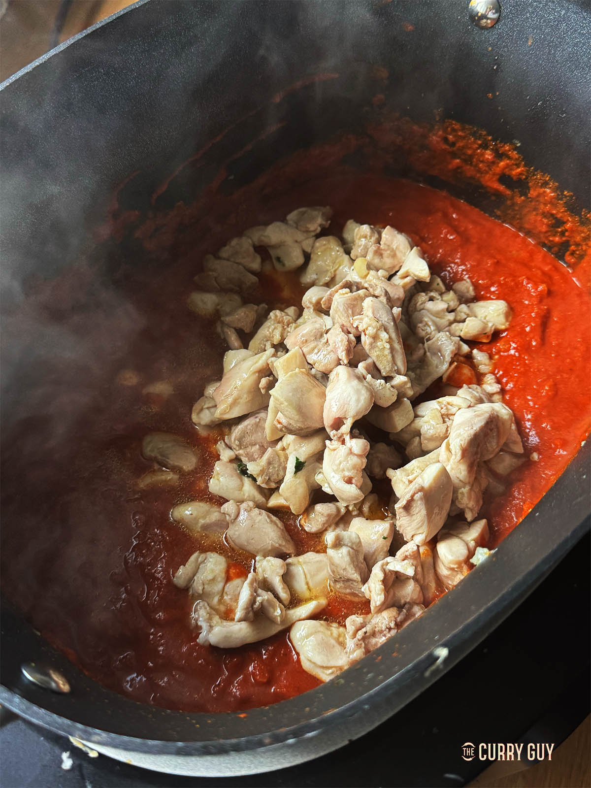 Returning the chicken to the slow cooker with the chicken stock or water. 