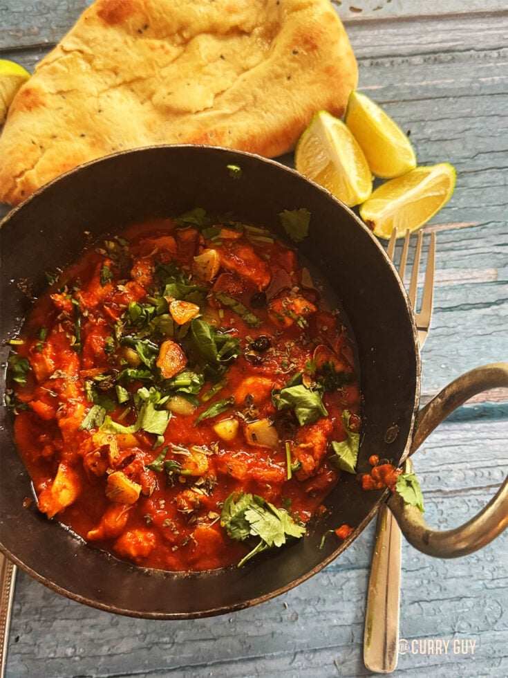 Slow cooker chicken chilli garlic curry next to naans.