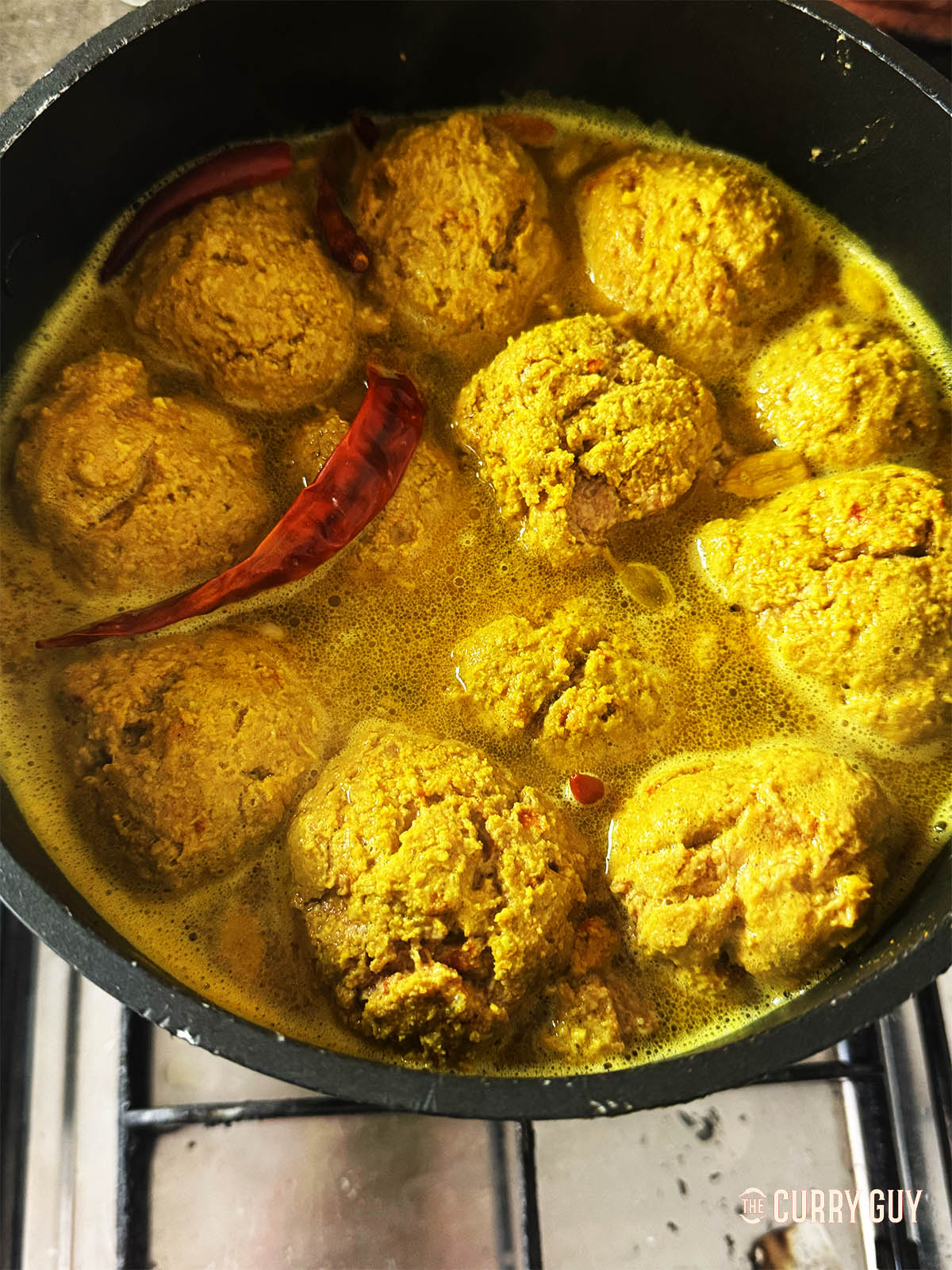 Simmering the meatballs in the spiced cooking liquid.