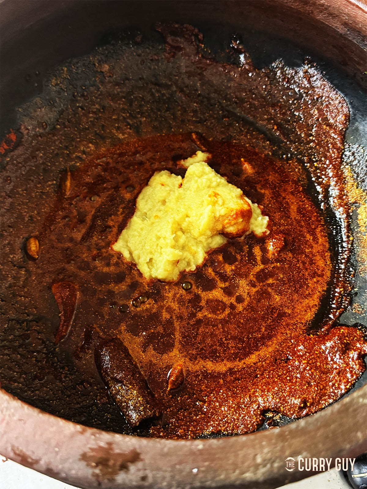 Adding garlic and ginger paste to the pot.